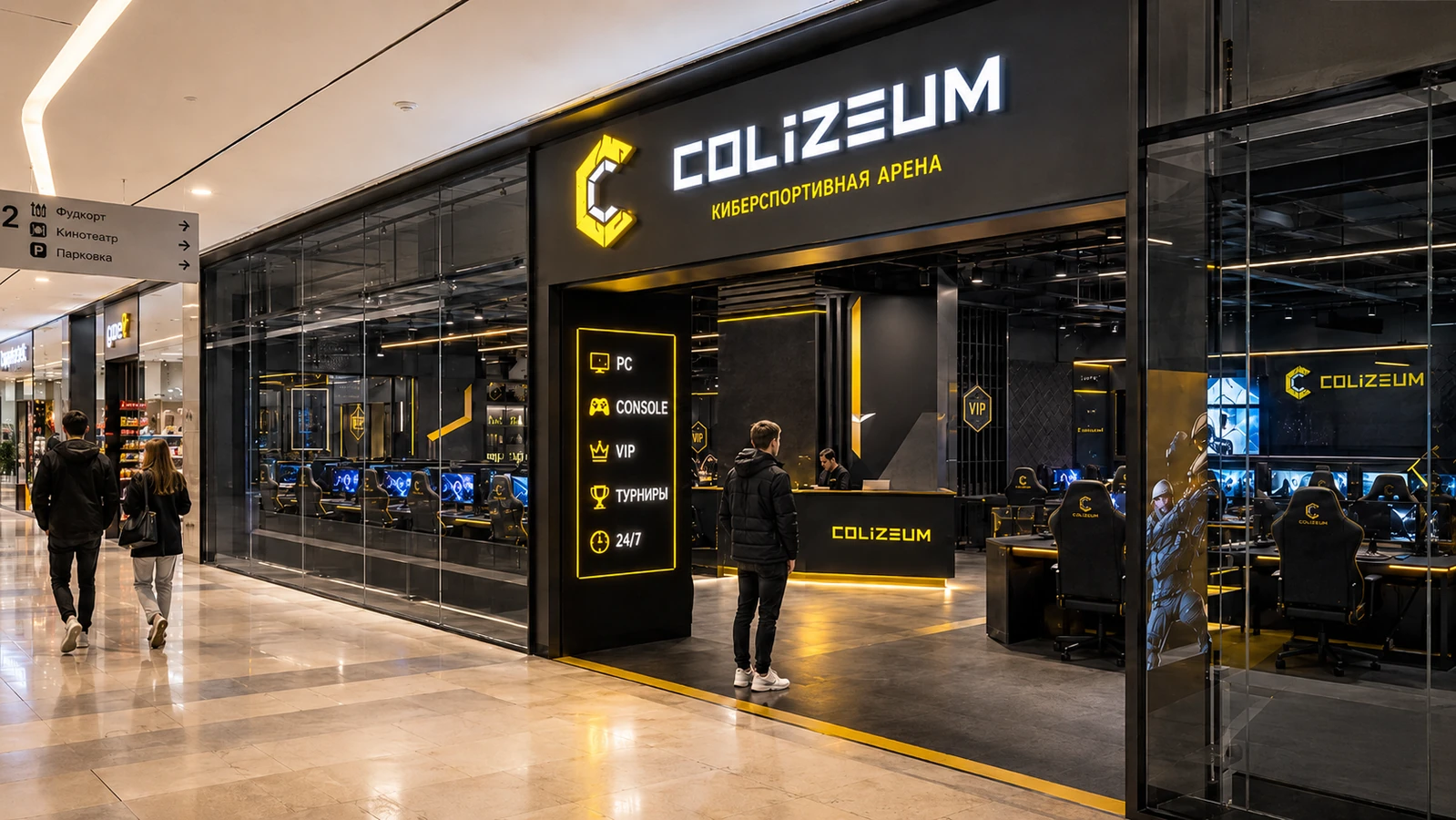 Современный фасад компьютерного клуба и киберспортивной арены «Colizeum» в торговом центре. Вход оформлен в фирменных черных и ярко-желтых цветах с подсвеченной вывеской.